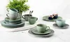 A collection of ceramic tableware, including cups, saucers, and plates, arranged on a tray and a table. Produktbild-Vorschau