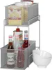 A two-tier mesh storage rack filled with various food and drink items, including bottles, cans, and a box of food. There are also white bowls stacked to the right of the rack. Produktbild-Vorschau