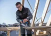 A man is using a circular saw on a wooden plank on a construction site. Anteprima dell’immagine prodotto