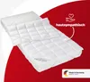 A quilted mattress topper is shown layered over a mattress on a diagonal view against a red and white background. Produktbild-Vorschau