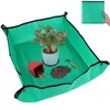 A green plant potting mat with a potted plant, a small red pot, and soil. Produktbild-Vorschau
