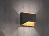 A modern wall lamp with a black and wood finish is mounted on a concrete wall. Podgląd zdjęcia produktu