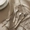 A set of cutlery is laid out on a checkered tablecloth and a grey napkin. Anteprima dell’immagine prodotto