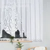 A close-up view of a white lace curtain hanging in a window. Anteprima dell’immagine prodotto