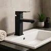 A black faucet is installed on a white sink in a bathroom. Podgląd zdjęcia produktu