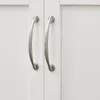 A close-up view of two silver cabinet handles on a white cabinet door. Produktbild-Vorschau