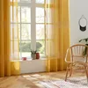 A room with yellow curtains, a wicker chair, and a rug. Produktbild-Vorschau