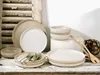 A collection of stoneware dinnerware, including plates and bowls, arranged on a rustic wooden surface. Náhľad obrázku produktu