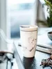 A marble-patterned coffee mug with a lid sits on a dark countertop next to a set of keys. Voir les images du produit
