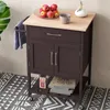 A kitchen cart with a wooden top, a drawer, and double doors, placed on a patterned rug. Voir les images du produit