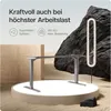 A modern standing desk frame is displayed on a circular platform, with a large rock formation and a unique lamp in the background, set against a sandy, desert-like environment. Produktbild-Vorschau