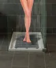 A person's legs are shown standing in a shower on a grey slatted shower mat. Produktbild-Vorschau