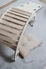 A wooden rocking toy for children is placed on a soft rug, with a beige cushion underneath. Produktbild-Vorschau