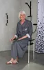 A woman is sitting on a shower stool in a modern bathroom. Produktbild-Vorschau