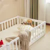 A white wooden toddler bed with a mattress and bedding, including two teddy bears and a pillow. Anteprima dell’immagine prodotto