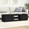 A black TV stand is placed in front of a sofa in a living room setting. Voir les images du produit