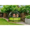 Two children are playing in a round, green pool with a transparent cover in a backyard setting. Produktbild-Vorschau