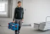 A man is walking through a construction site carrying a tool case. Anteprima dell’immagine prodotto