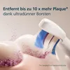 Close-up of a toothbrush head cleaning teeth, with glittery particles representing plaque. Produktbild-Vorschau