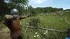 A person practicing archery in a field with targets in the background. Produktbild-Vorschau