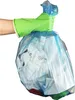A hand wearing a green glove holds a blue trash bag filled with white trash. Produktbild-Vorschau