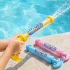 Hände eines Kindes, die eine gelbe Wasserpistole halten und aktiv Wasser in ein Schwimmbecken spritzen Produktbild-Vorschau