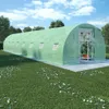 A large, green greenhouse structure is set up in a grassy yard with trees in the background and a blue sky with clouds above. Anteprima dell’immagine prodotto