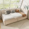 A beige upholstered daybed with a pull-out trundle bed, featuring a scalloped headboard and decorative pillows, set against a large window with a view of trees and houses. Náhled obrázku produktu