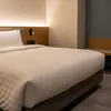 A close-up view of a neatly made hotel bed with white damask striped bedding. Produktbild-Vorschau