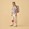A young girl wearing a backpack stands against a plain background. Voir les images du produit