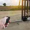 A hand holding a remote control, aiming it at an automatic gate opener. Voir les images du produit