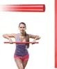 A woman is holding a red gym stick horizontally in front of her. Náhled obrázku produktu