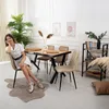 A woman is sitting on a chair next to a dining table in a well-lit room. Produktbild-Vorschau