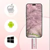 A smartphone displaying a cherry blossom wallpaper is connected to a pink USB drive. Icons for Apple, Android, and Windows are displayed on the left. Produktbild-Vorschau