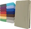 A stack of folded fitted sheets in various colors next to a single folded fitted sheet in beige. Produktbild-Vorschau