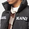 Close-up of a person wearing a black puffer jacket with white lettering. Voir les images du produit