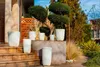 A collection of white planters arranged on steps and a stone wall in a garden setting. Anteprima dell’immagine prodotto