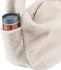 A close-up view of a fluffy cream-colored bag with a side pocket holding a copper and gray tumbler. Náhled obrázku produktu