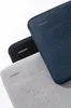 Three laptop sleeves are stacked on a white background. The sleeves are black, navy, and gray. The navy and gray sleeves have water droplets on them. Anteprima dell’immagine prodotto
