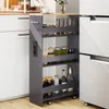 A narrow kitchen cart with four shelves filled with jars and bottles, placed between kitchen cabinets and a refrigerator. Podgląd zdjęcia produktu