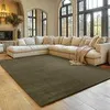 A living room with a large sectional sofa and a green rug. Produktbild-Vorschau