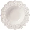 A white ceramic bowl with a scalloped edge, decorated with embossed festive motifs and stars. Produktbild-Vorschau