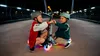Two children wearing helmets are playing with a scooter on a bridge at night. Podgląd zdjęcia produktu