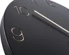 Close-up view of a black wall clock face with gold hour markers. Produktbild-Vorschau