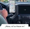 A person's hand is on the steering wheel of a car, with a smartphone mounted on the dashboard. An Amazon Echo Auto device is plugged into the car's power outlet. Podgląd zdjęcia produktu