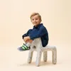 A young boy is sitting on a unique, animal-shaped stool. Produktbild-Vorschau