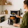 A woman is using a digital air fryer in a kitchen setting. Produktbild-Vorschau