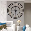 A large vintage-style wall clock is mounted on a gray wall above a white sofa. A gold lamp sits on a side table next to the sofa. Produktbild-Vorschau