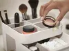 A hand is placing a makeup product into a cosmetic organizer. Náhled obrázku produktu