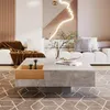 A modern living room scene with a white sectional sofa, a large square coffee table, and abstract art on the wall. Produktbild-Vorschau